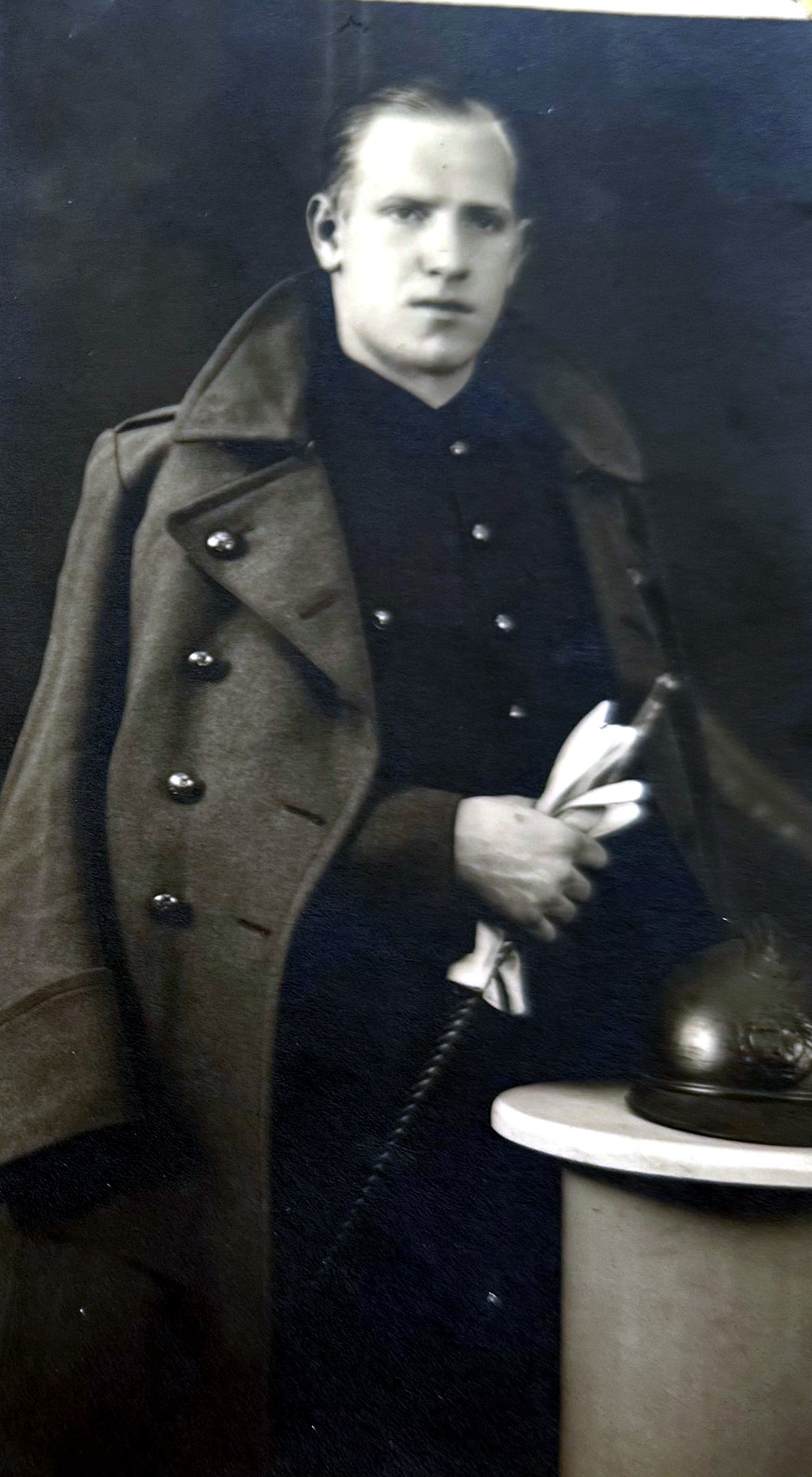 Portret van soldaat François Stevens in overjas, met zijn Adrianhelm op een sokkel, 1940